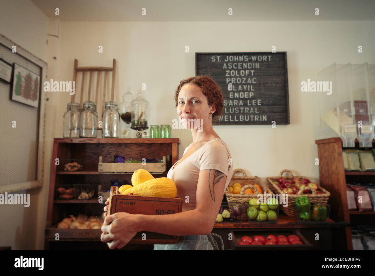 Porträt von weiblichen Verkäuferin mit Obst und Gemüse Kiste im Dorfladen Stockfoto