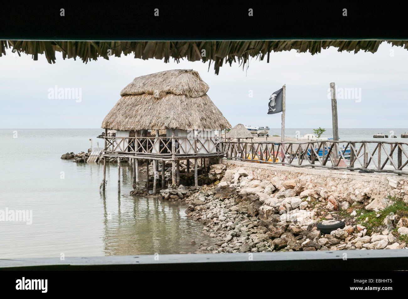 Gestelzt Strohdach Speisesaal Terrasse über dem Wasser mit zerfetzte Piratenflagge weht im Wind, Bucht von Campeche, Campeche, Mexiko. Stockfoto