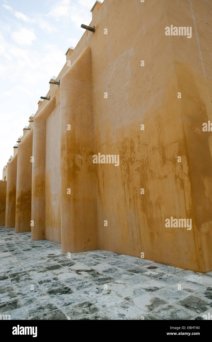 Seitenansicht der Iglesia de Jesus Kirche, die ockerfarbenen adobe Mauer, Stein, Fliesen- Bürgersteig und blauer Himmel, Campeche, Mexiko. Stockfoto