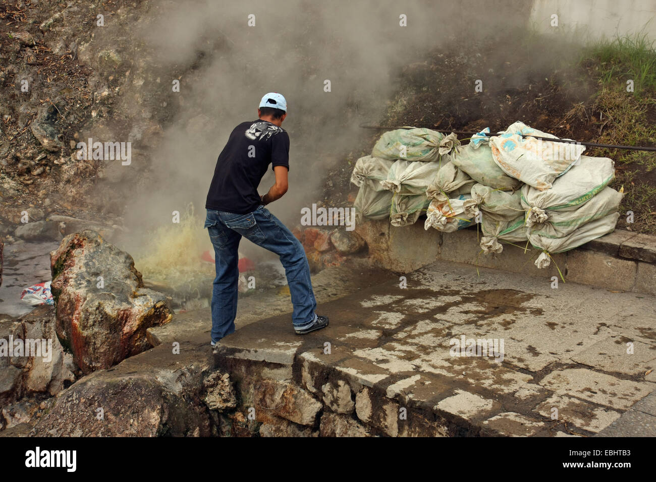 Mann kochen sacs von Maiskolben in einer heißen Quelle mit natürlich kochendes Wasser in Furnas, Insel São Miguel, Azoren, Portugal. Stockfoto