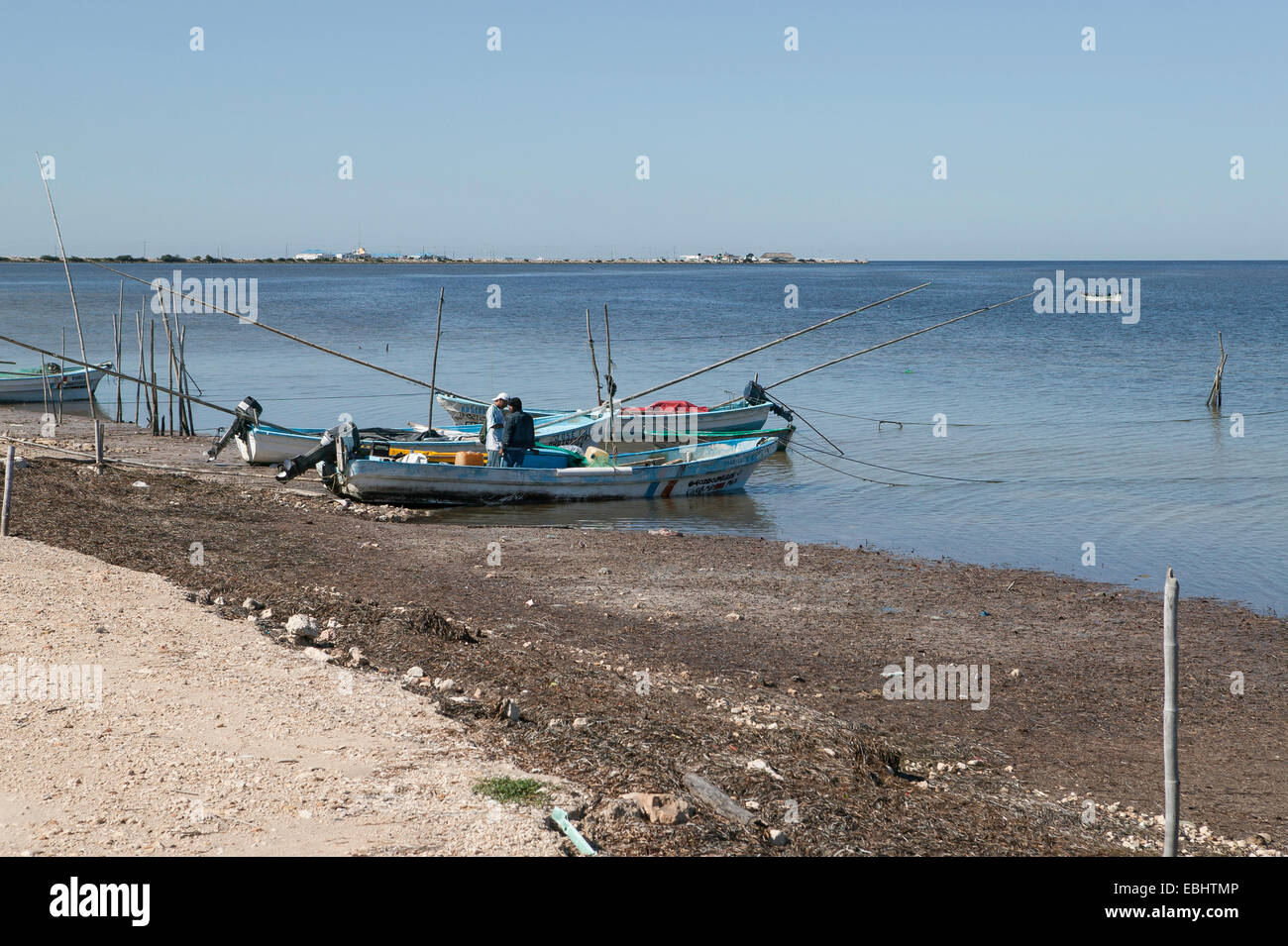 Zwei Fischer stehen in einem der vielen Strände panga Boote mit langen Bambus Angeln entlang der guf von Mexiko Shoreline in Campeche, Mexiko. Stockfoto