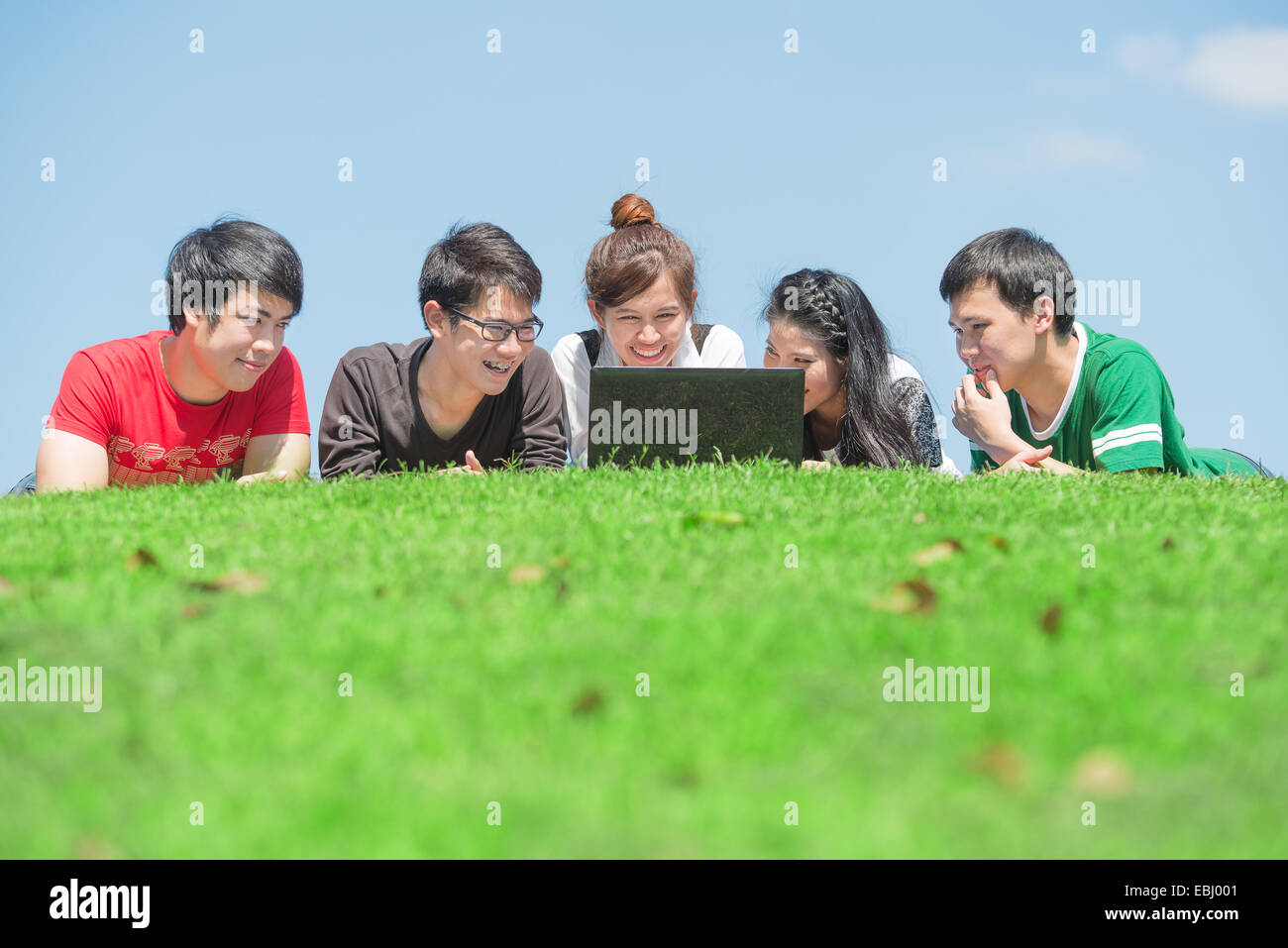 Gruppe von Studenten im Freien auf dem Rasen liegen und auf der Suche nach computer Stockfoto