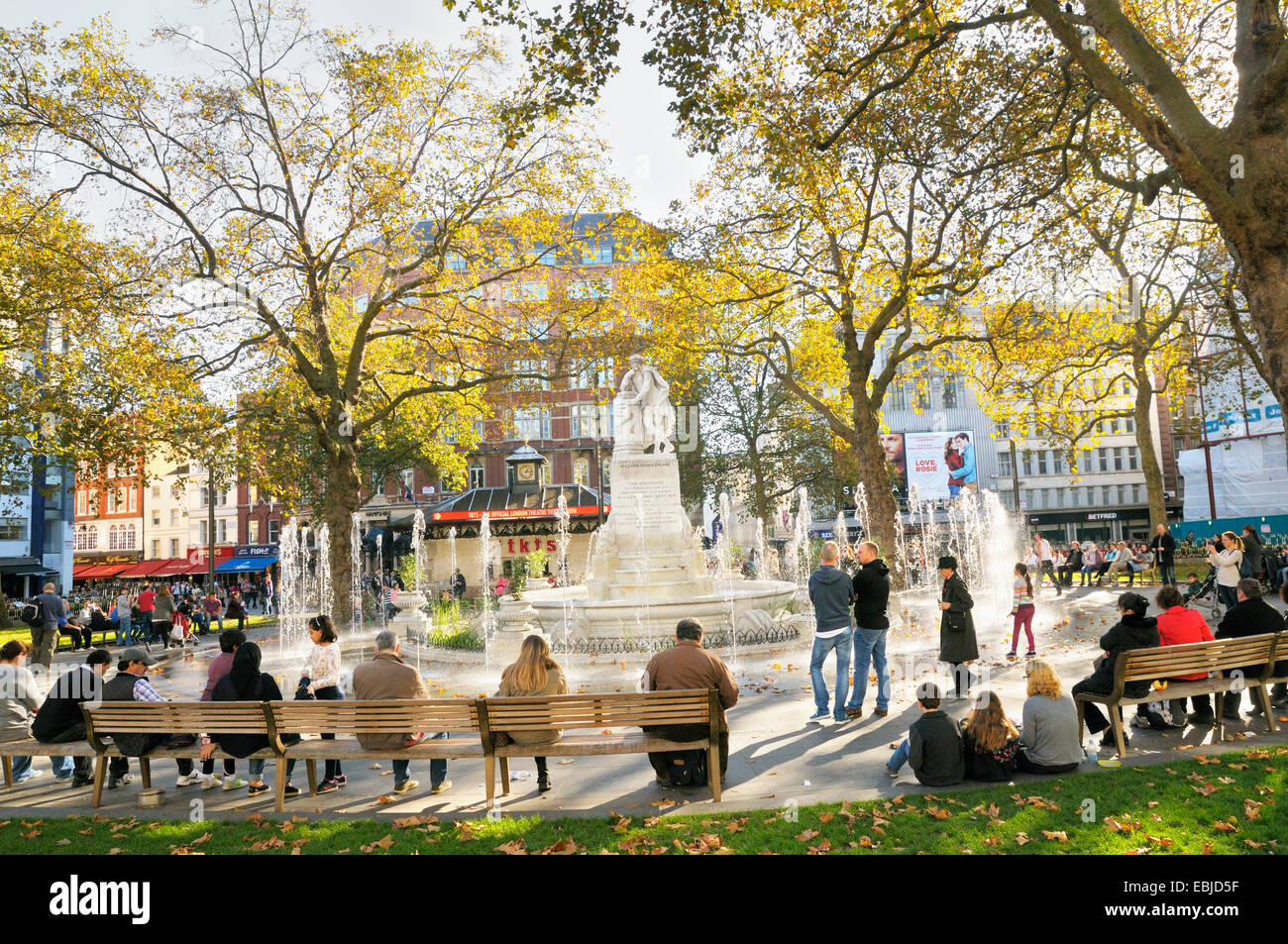 Leicester Square in London.  Menschen rund um die Statue von William Shakespeare und Brunnen in Leicester Square Gardens entspannen. Stockfoto