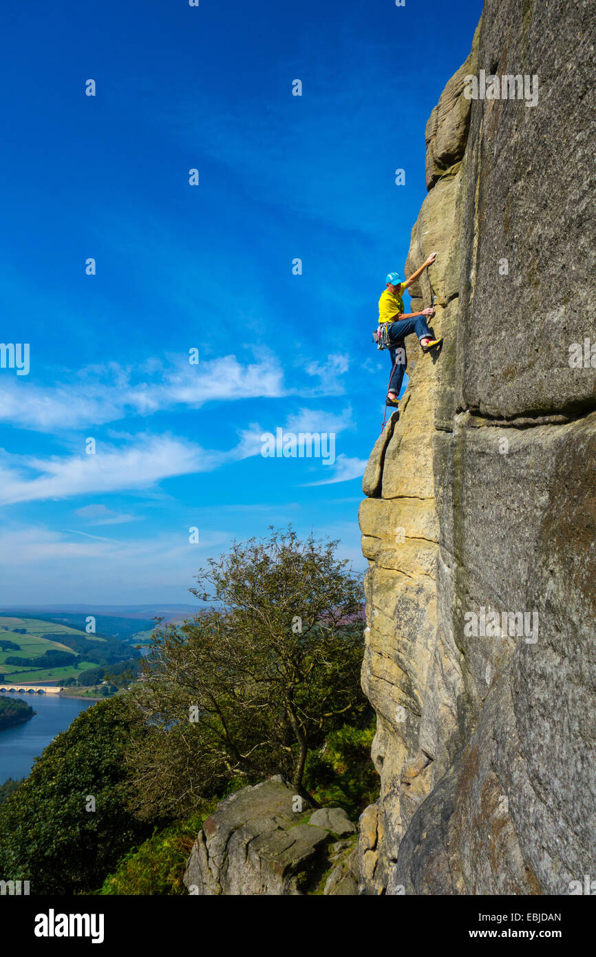 Kletterer in Gelb auf Bamford Kante, Derbyshire, Peak District, mit Ladybower Reservoir hinter Stockfoto