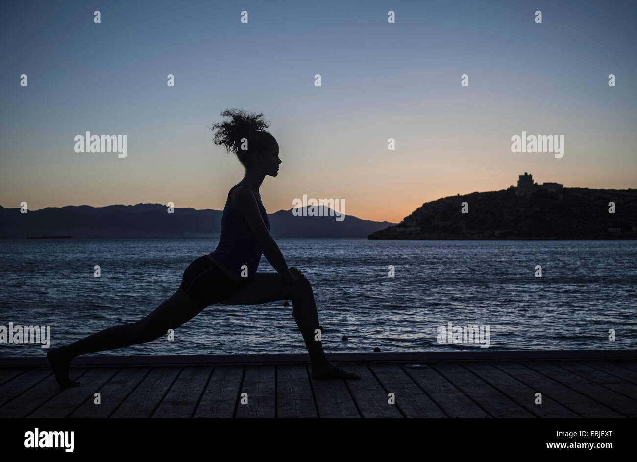 Junge Frau beim Yoga auf dem Seeweg, Silhouette Stockfoto