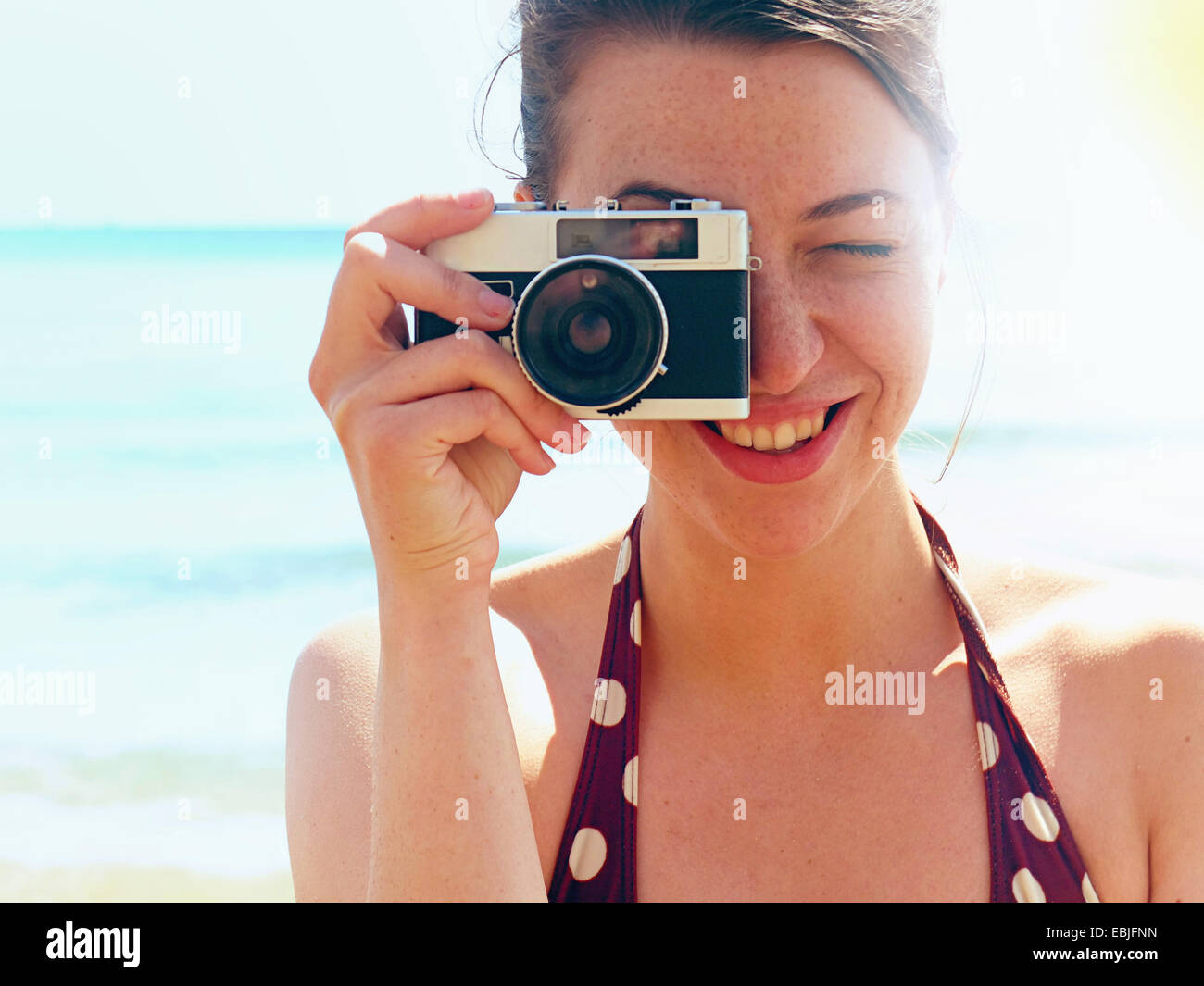 Junge Frau mit Kamera am Strand Stockfoto