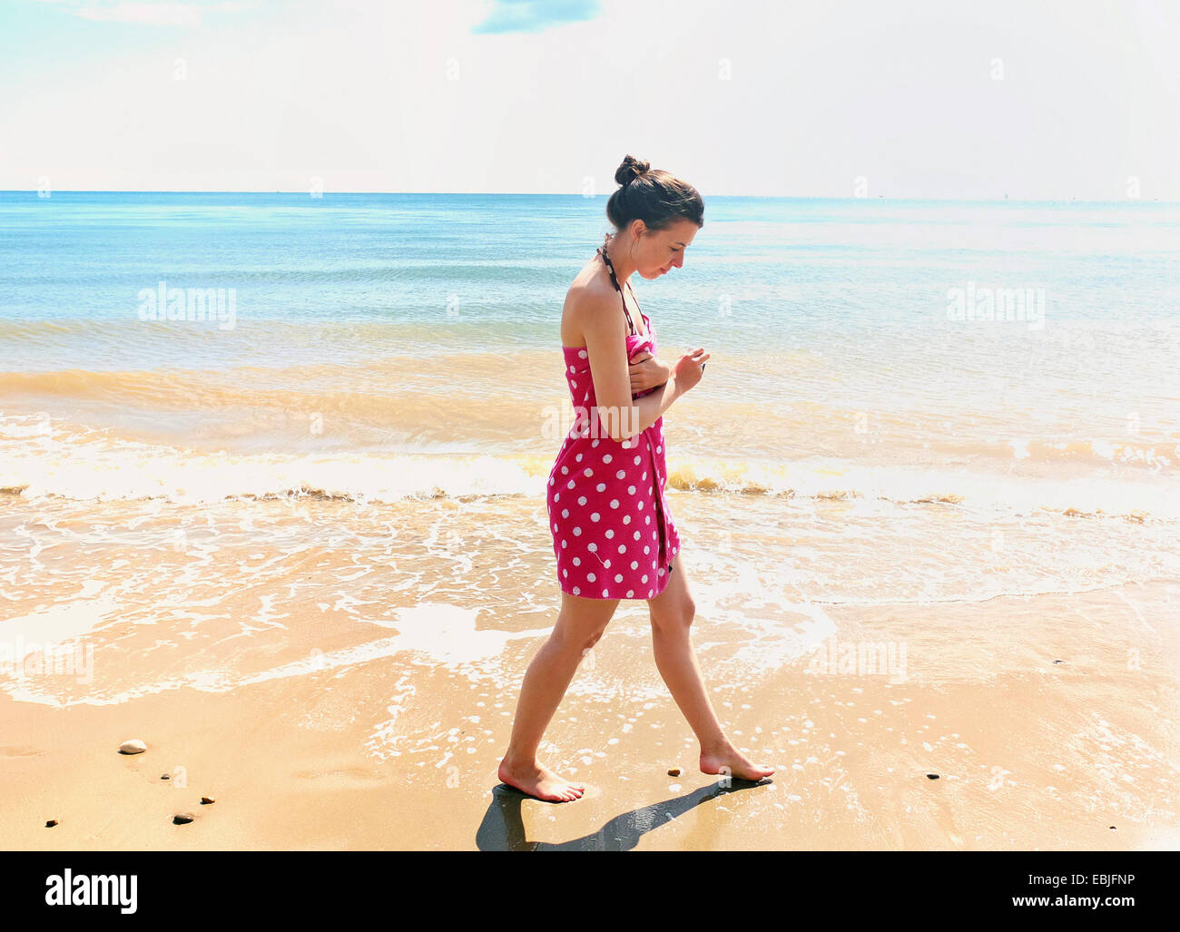Junge Frau, die zu Fuß am Strand Stockfoto