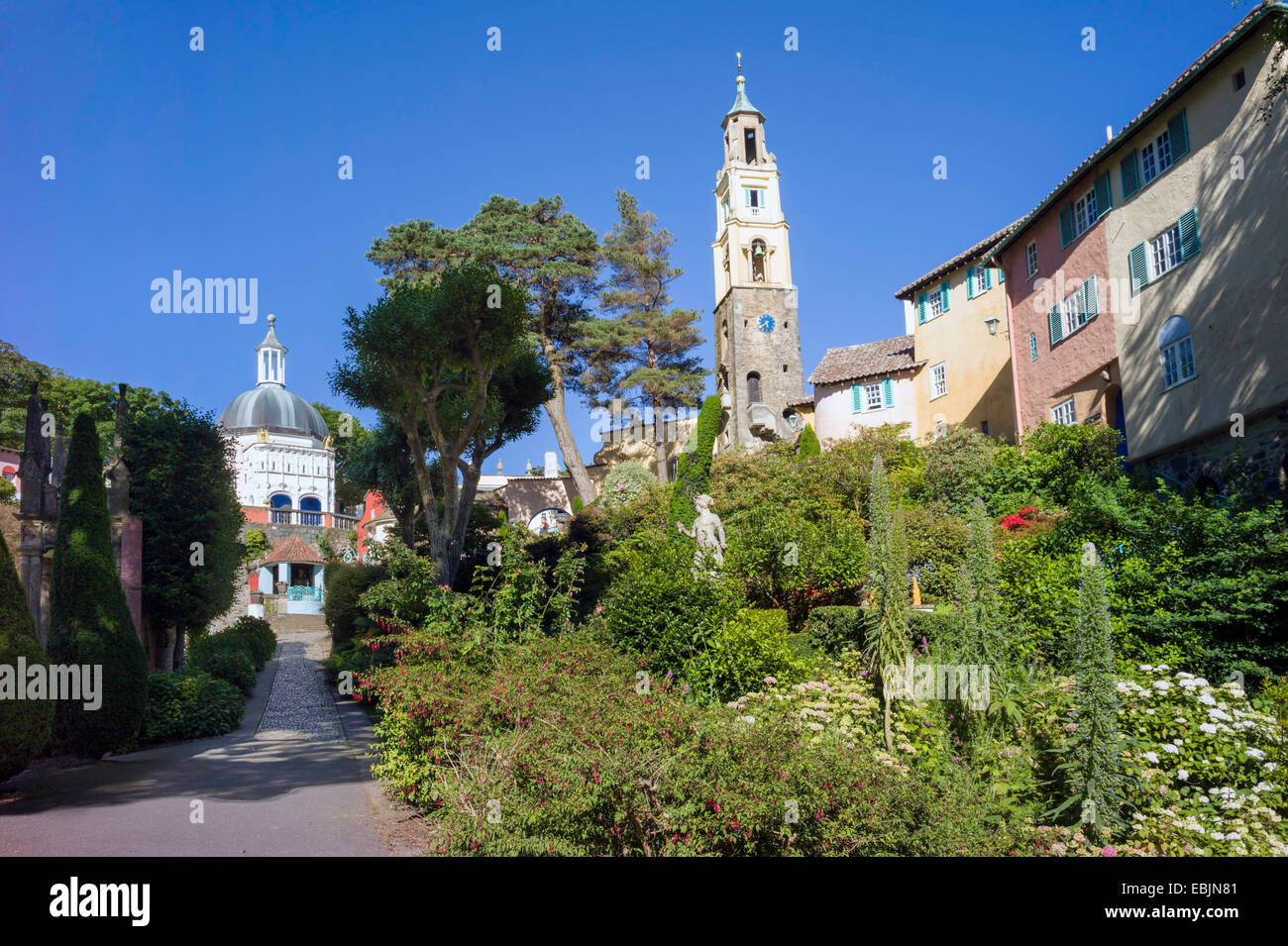 Wege-Thread durch Sträucher, Blumen und Bäume in Batterie quadratische Portmeirion Dorf überragt von italienischen Stil Gebäuden Stockfoto