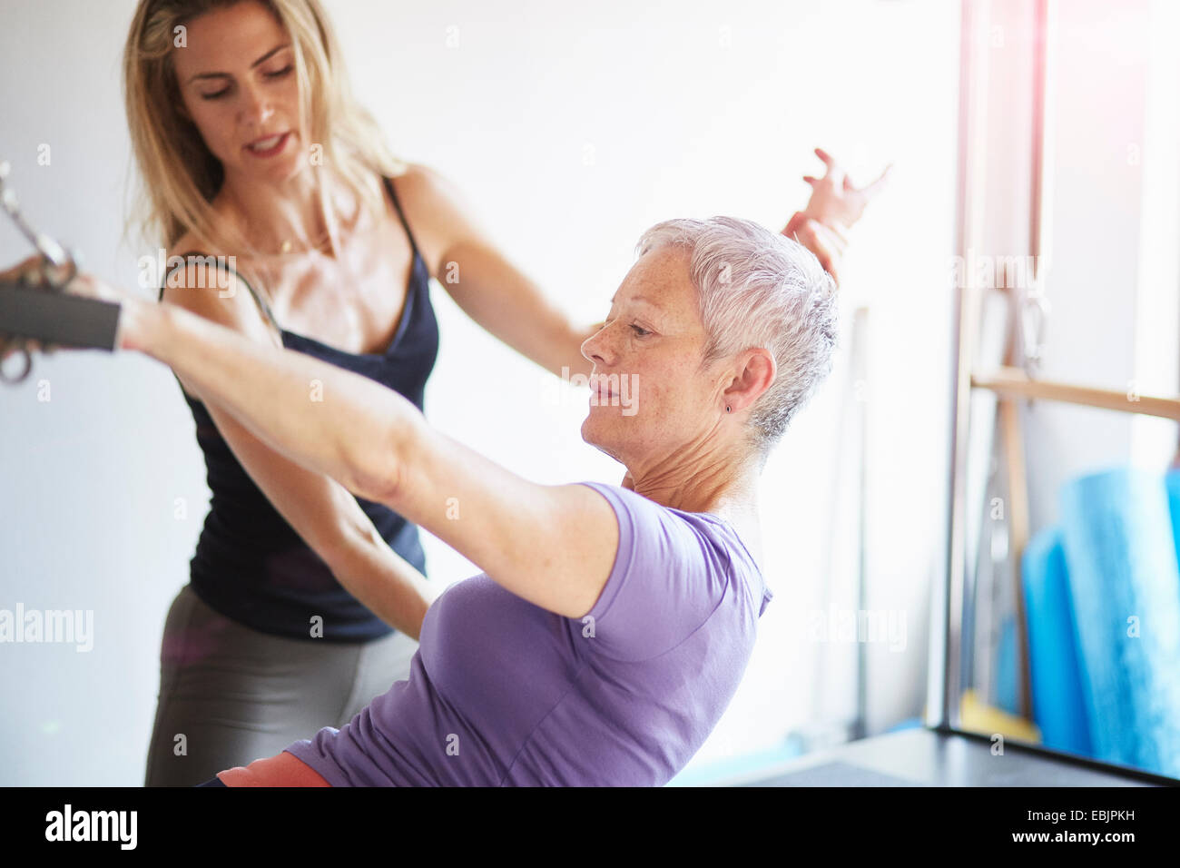 Weibliche Schüler und Lehrer praktizieren Pilates auf Trapez-Tisch in Pilates-Fitness-Studio Stockfoto