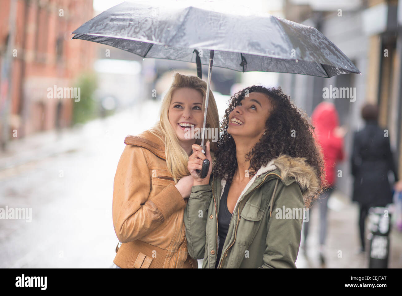 Junge Frauen, die bergende unter Dach Stockfoto