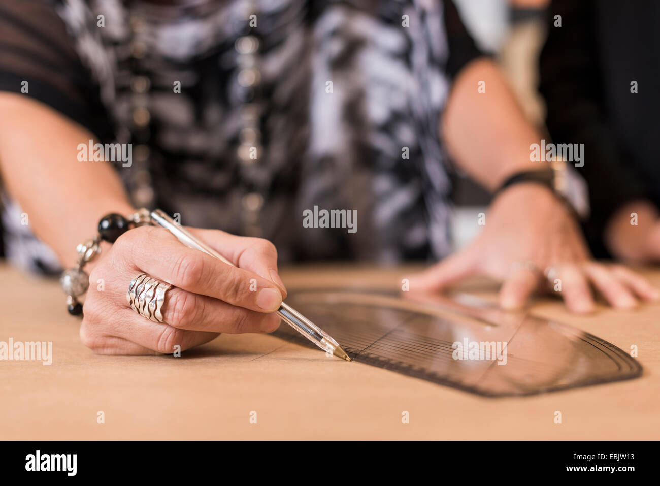 Nahaufnahme von Reifen Näherin zeichnen mit gebogenen Herrscher auf Schneiderinnen Muster in Werkstatt Stockfoto