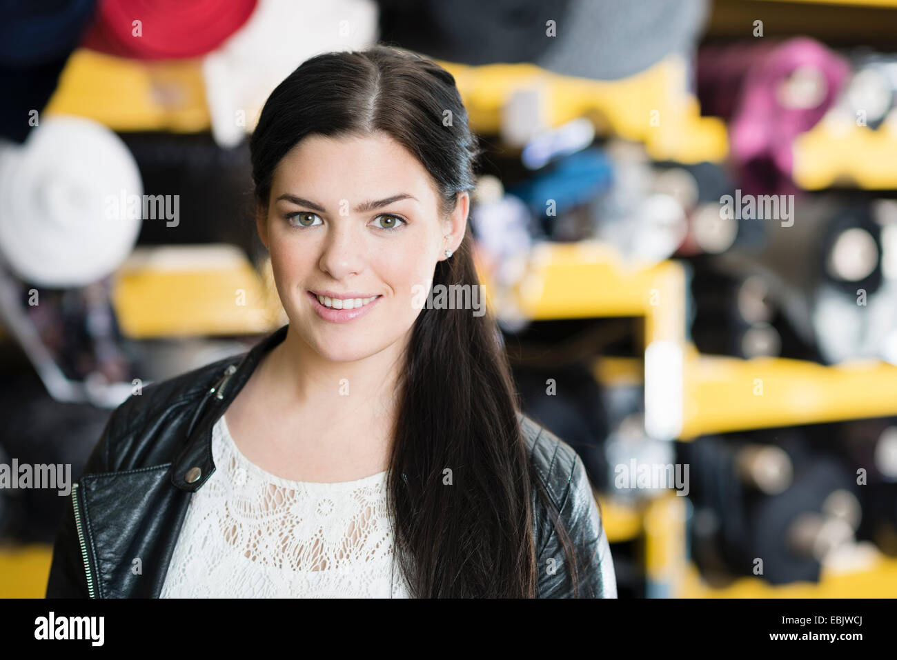 Porträt der jungen Näherin vor Textil Regalen in Werkstatt Stockfoto