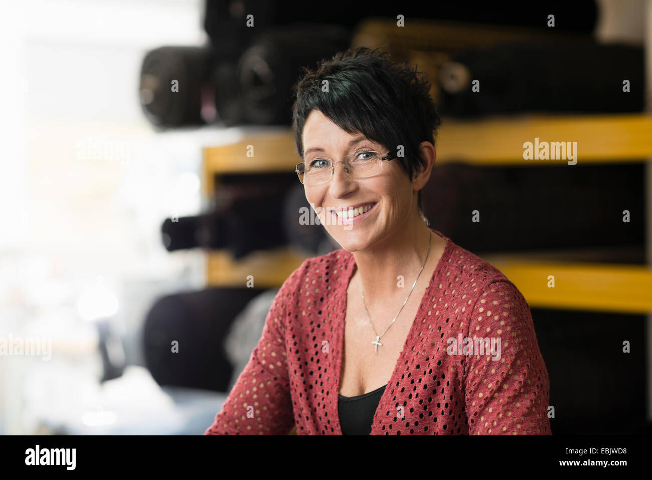 Porträt von Reifen Näherin vor Textil rollt in Werkstatt Stockfoto