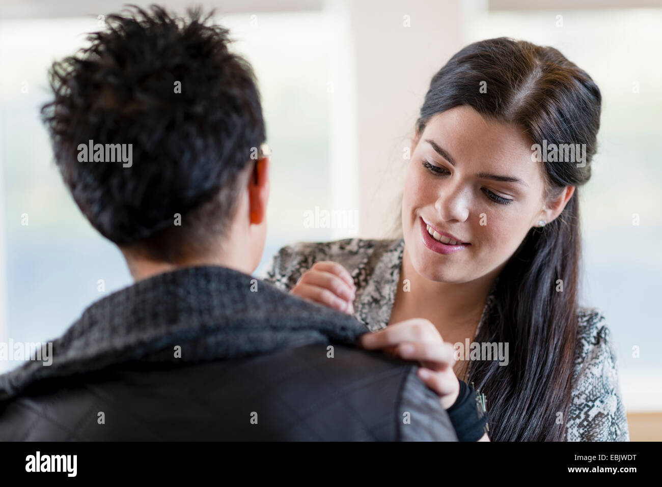 Junge Schneiderin, die Anpassung der Schulter des Kunden Jacke in Werkstatt Stockfoto