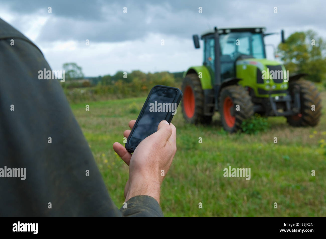 Männlichen Bauern Hand hochhalten Smartphone im Feld Stockfoto