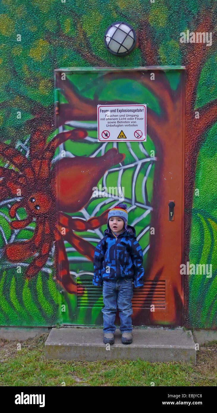 kleiner Junge stand vor einem bunt bemalten Wand einen Kindergarten, Spinne im Netz, Deutschland Stockfoto