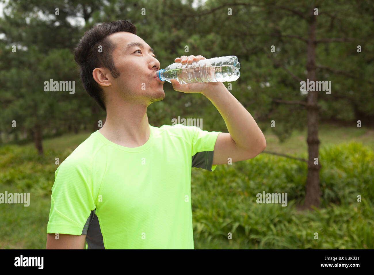 Junge männliche Läufer, abgefülltes Wasser zu trinken, im park Stockfoto