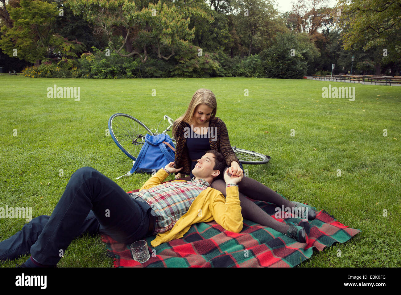 Junges Paar Hand in Hand auf der Picknickdecke im park Stockfoto