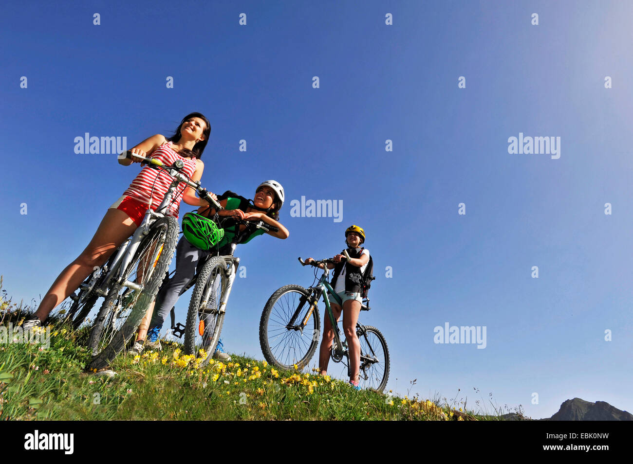 drei Jugendliche mit Mountainbikes stehen in Bergwiese, Frankreich, Savoie Stockfoto