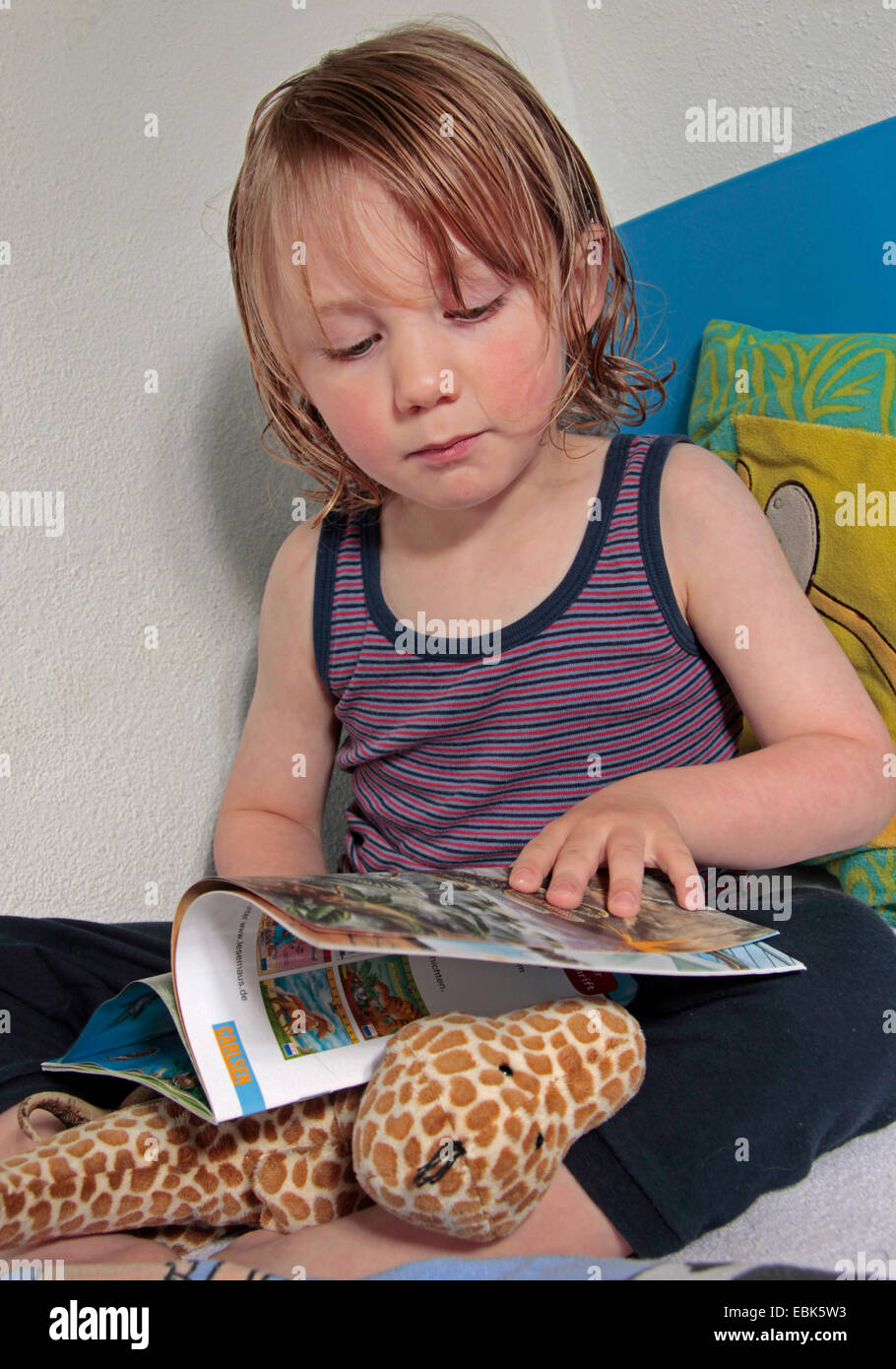 kleiner Junge im Bett mit nassen gekämmte Haar sieht bei einem Märchenbuch, Deutschland Stockfoto