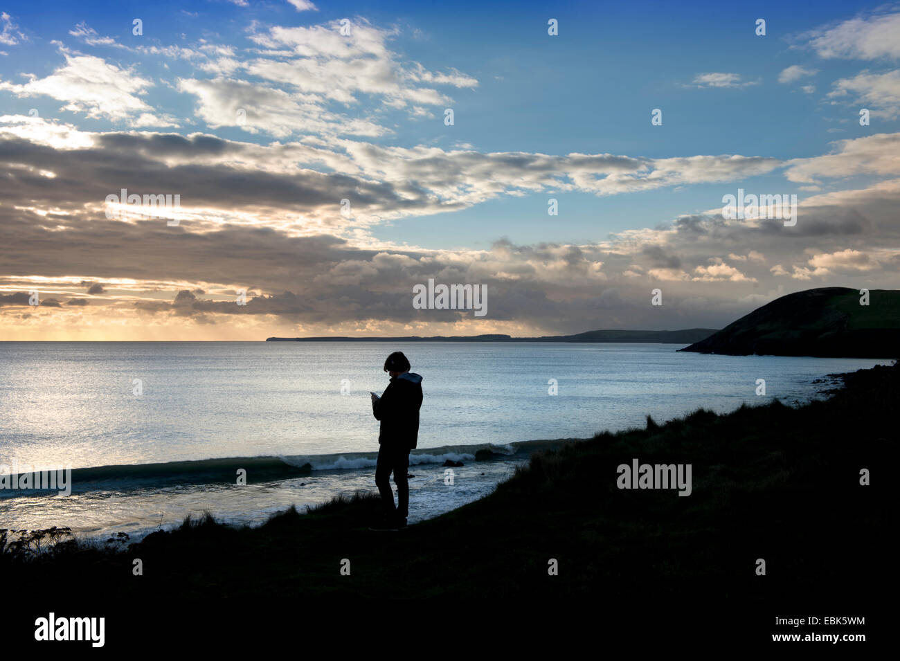 Ein Teenager hört auf seinem iPod beim Betrachten der Aussicht bei Manorbier Bay in der Nähe von Tenby in Pembrokeshire, Wales UK Stockfoto