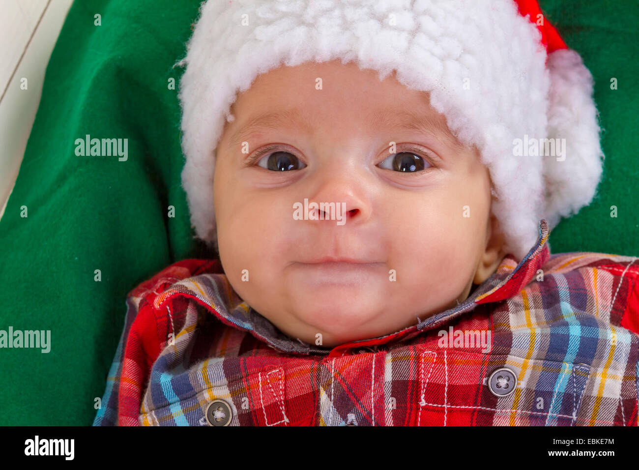 niedliche Baby Boy lächelnd in eine Weihnachtsmann-Mütze Nahaufnahme Stockfoto