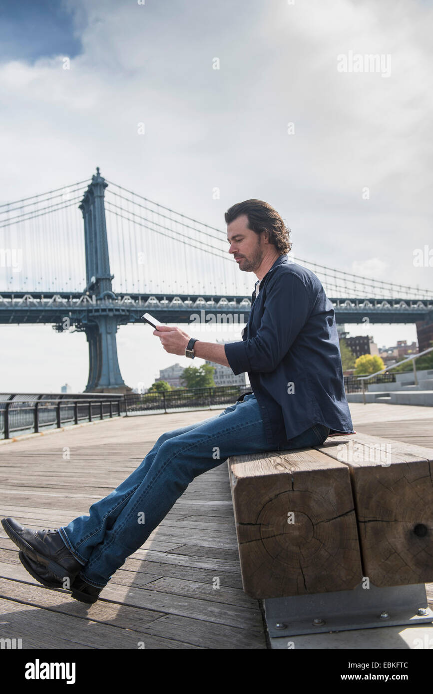 Mann mit TabletPC, Manhattan Bridge im Hintergrund, Brooklyn, New York State, New York City, USA Stockfoto