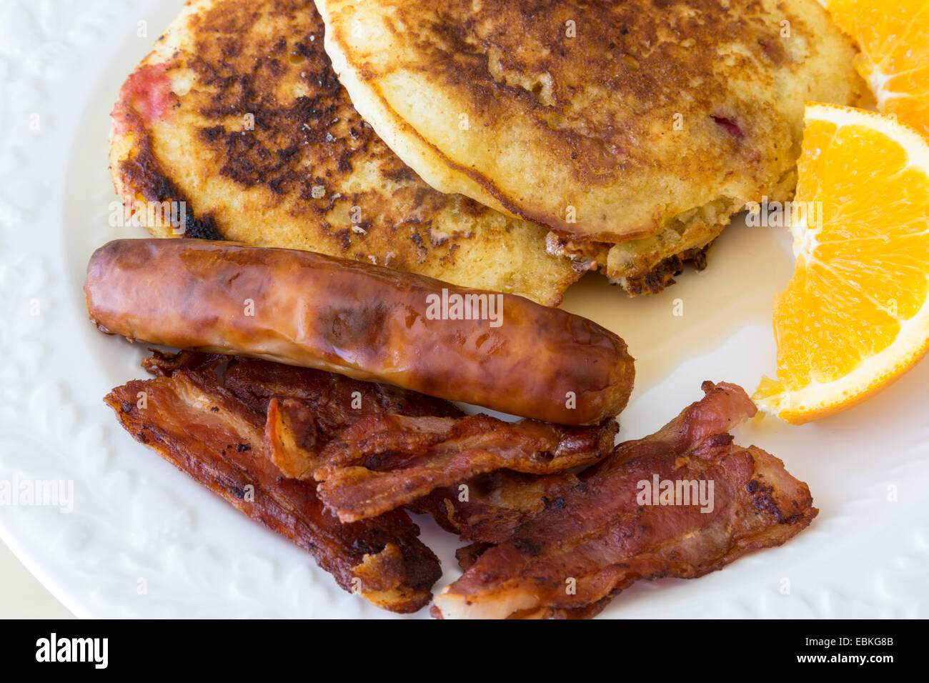 Frühstückswurst, Speck und Pfannkuchen mit einer Orangenscheibe. Stockfoto