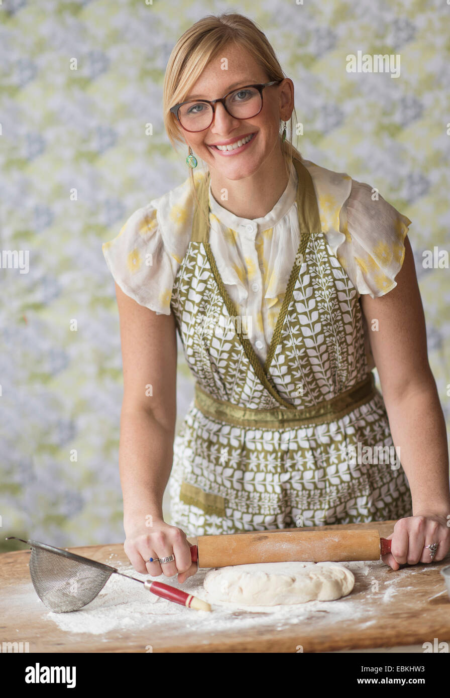 Lächelnde Frau mit Nudelholz beim Kneten von Teig Stockfoto