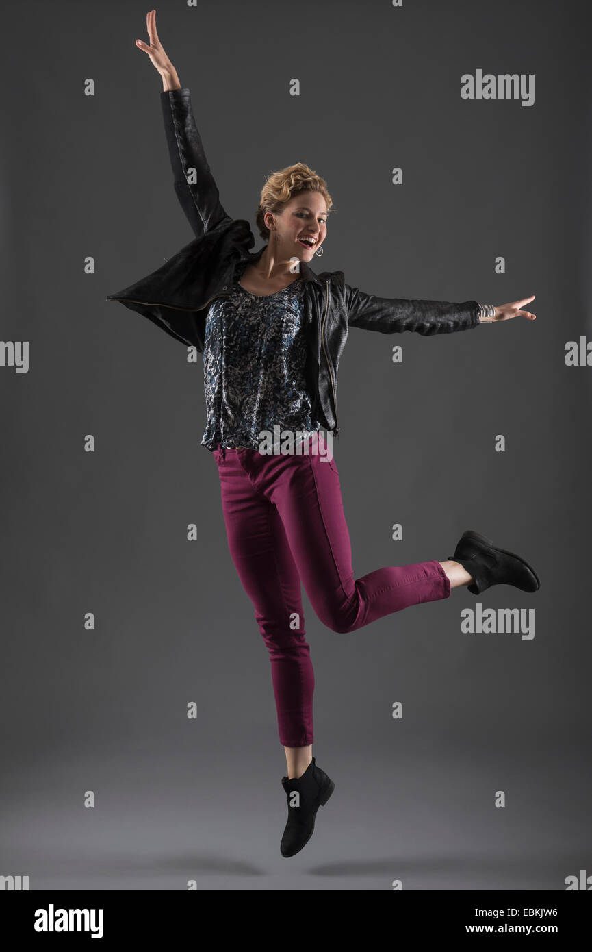 Studioaufnahme der stets gut gelaunte Frau mit erhobenen Armen springen Stockfoto