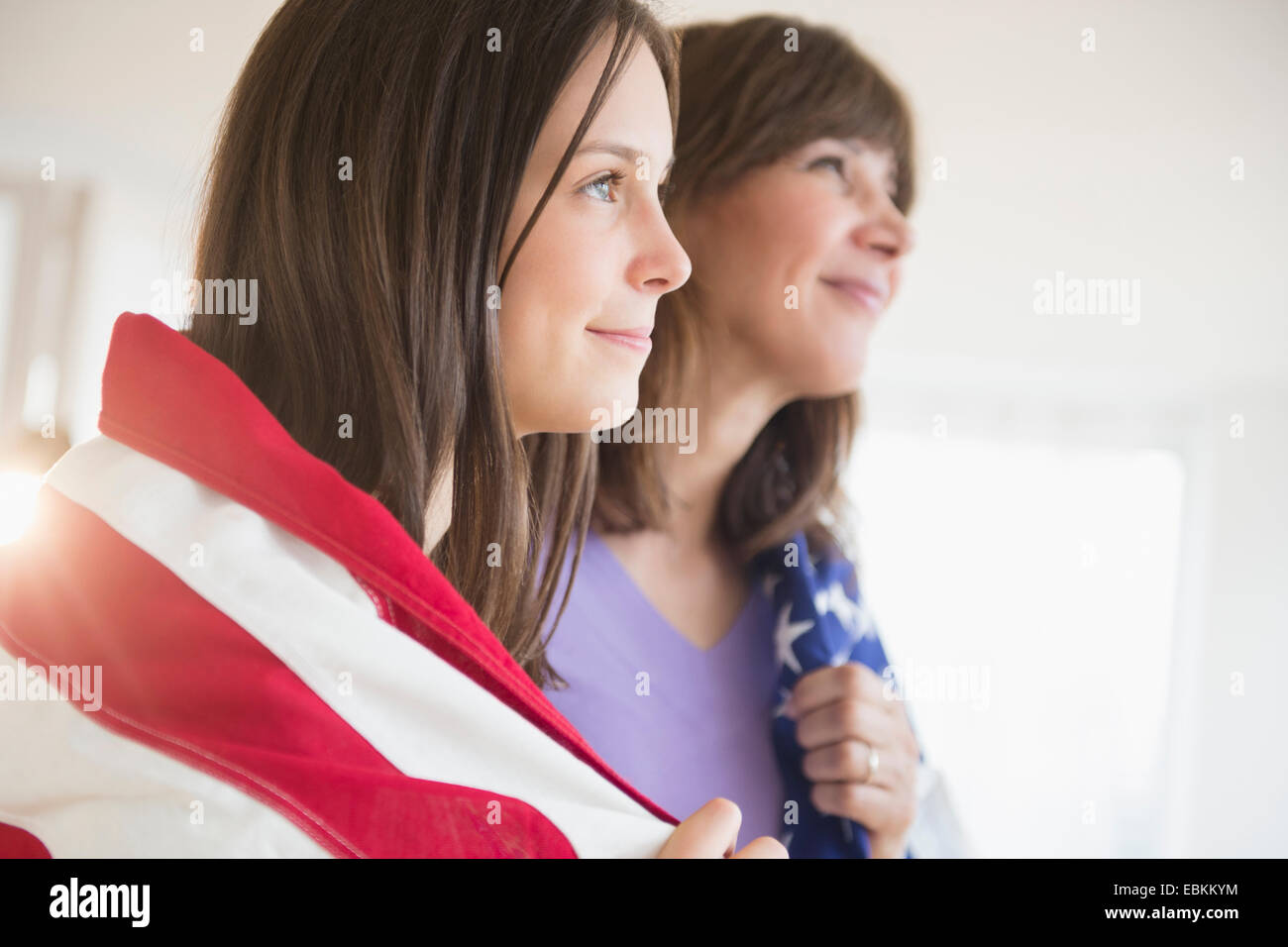 Teenager-Mädchen (14-15) und ihre Mutter gewickelt in amerikanische Flagge auf Fourth Of July Stockfoto