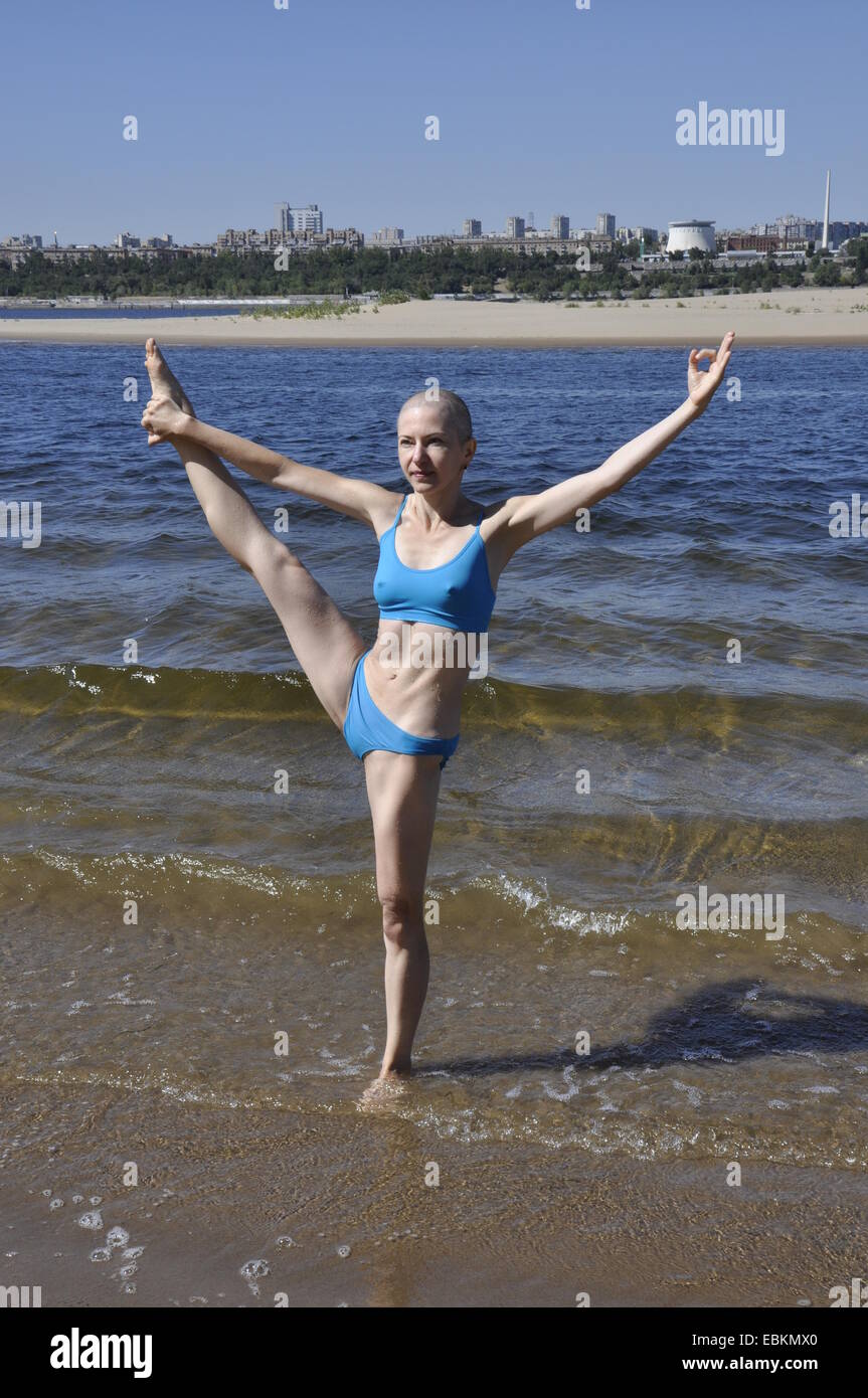 Glatze Frau stehen in Yogaposition genannt erweitert Hand To Big Toe darstellen oder Utthita Hasta Padangusthasana am Sandstrand Stockfoto