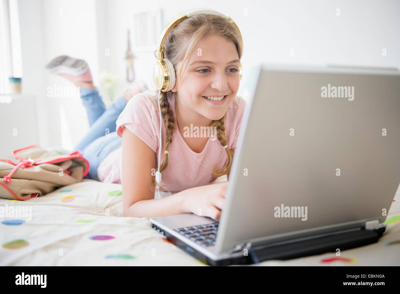 Mädchen (12-13) liegen im Bett mit laptop Stockfoto