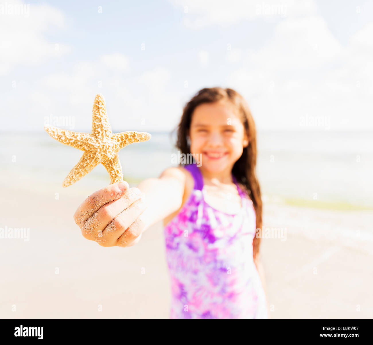 USA, Florida, Jupiter, Porträt von Mädchen (6-7) Holding Seestern am Strand Stockfoto