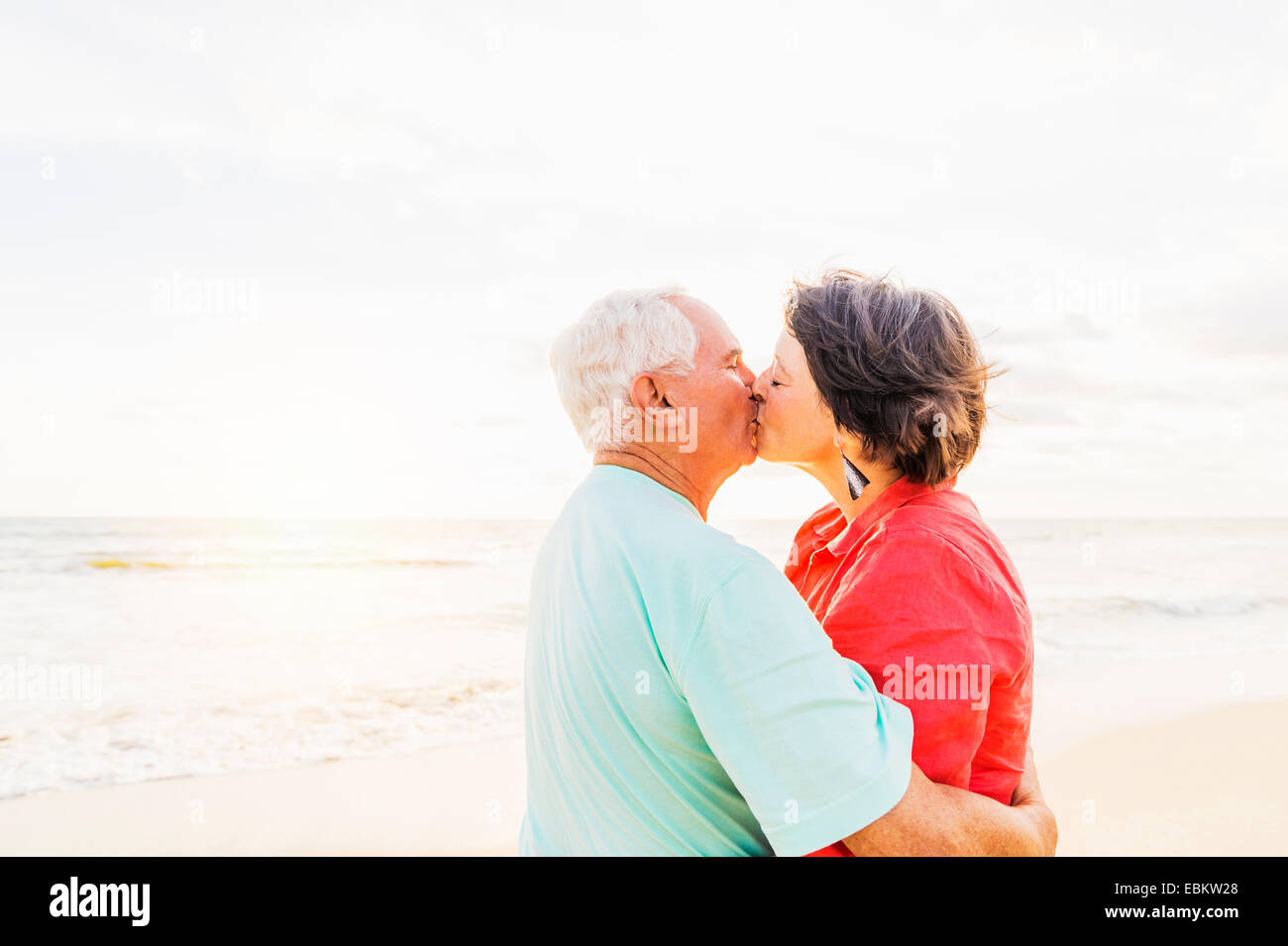 USA, Florida, Jupiter, älteres Paar küssen am Strand bei Sonnenaufgang Stockfoto