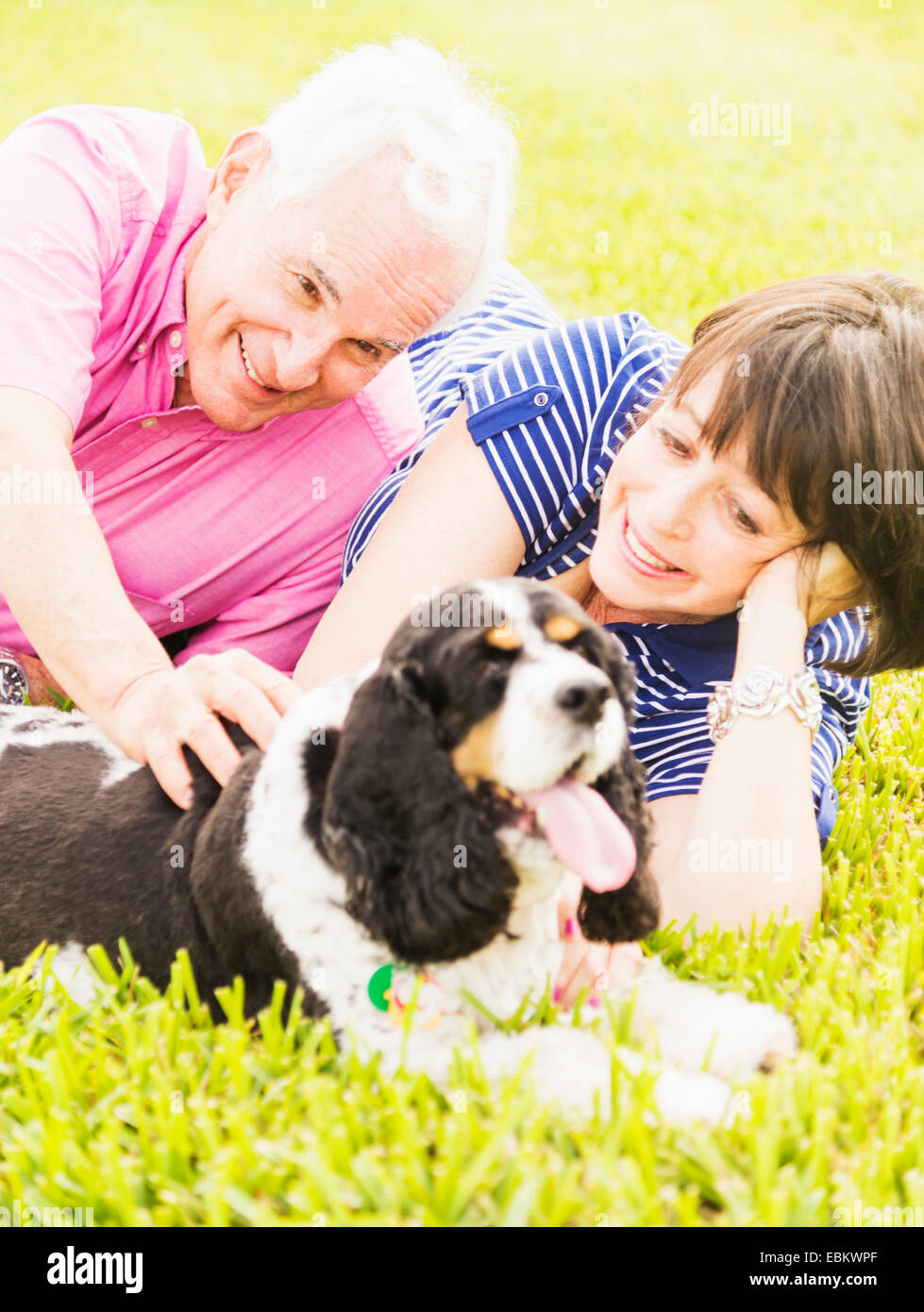 Lächelnde paar mit Hund im Grass liegen Stockfoto