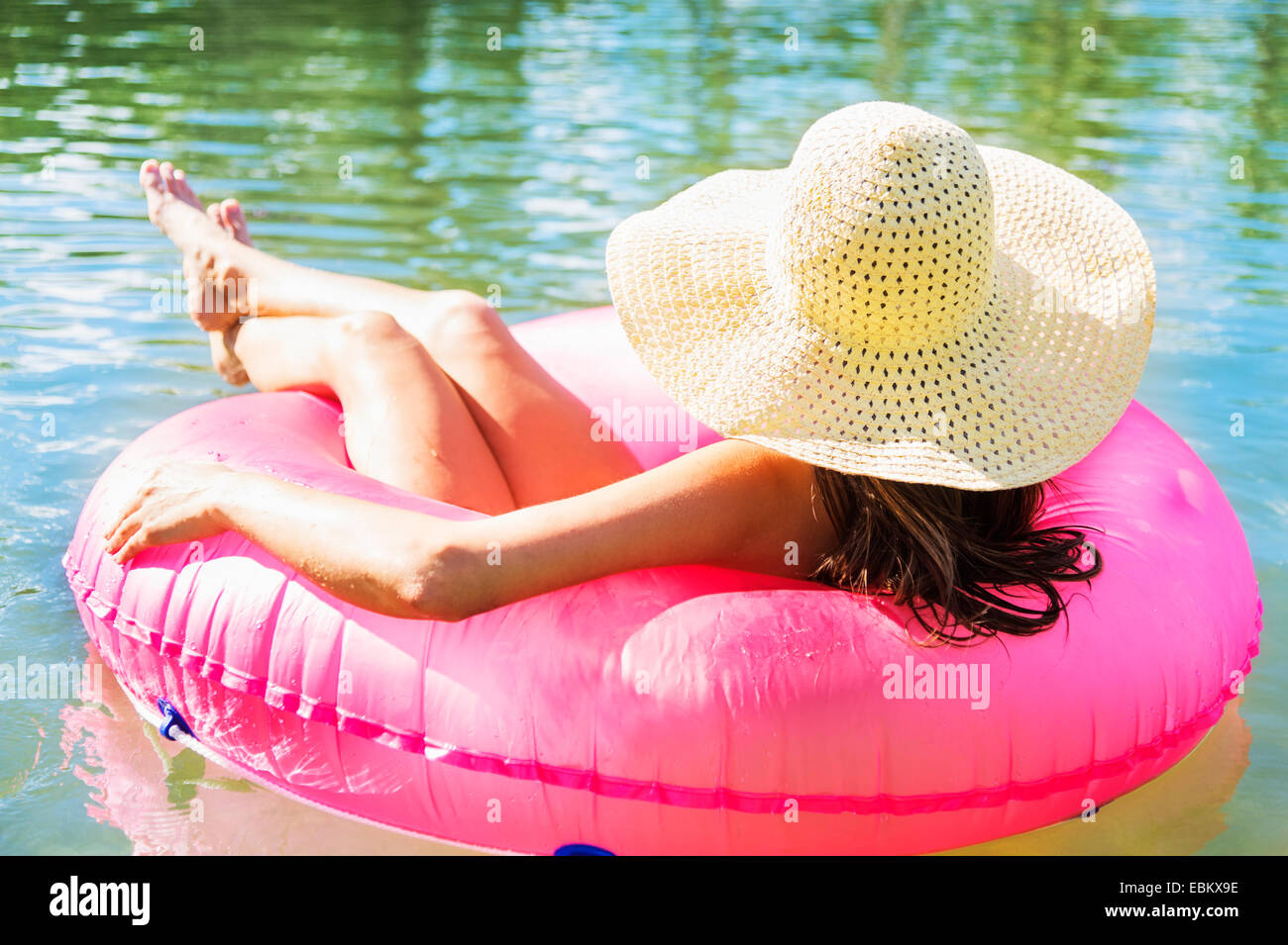 Rückansicht des jungen Frau mit Sonnenhut schwimmend auf Schwimmring Stockfoto