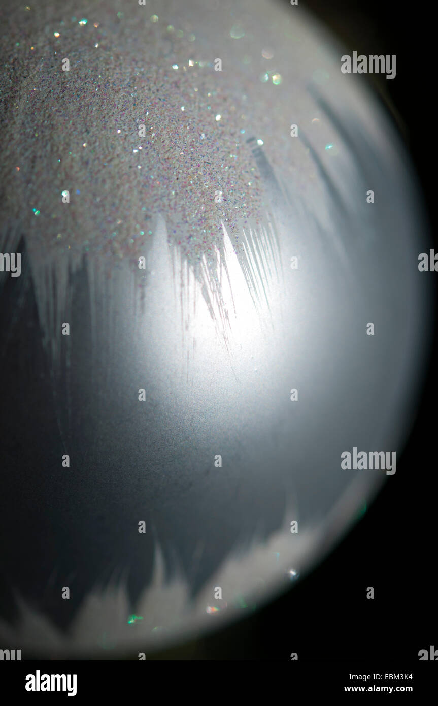 Silberne Christbaumkugel mit glitzernden Schnee-Effekt. Extreme Nahaufnahme mit dunklem Hintergrund. Stockfoto