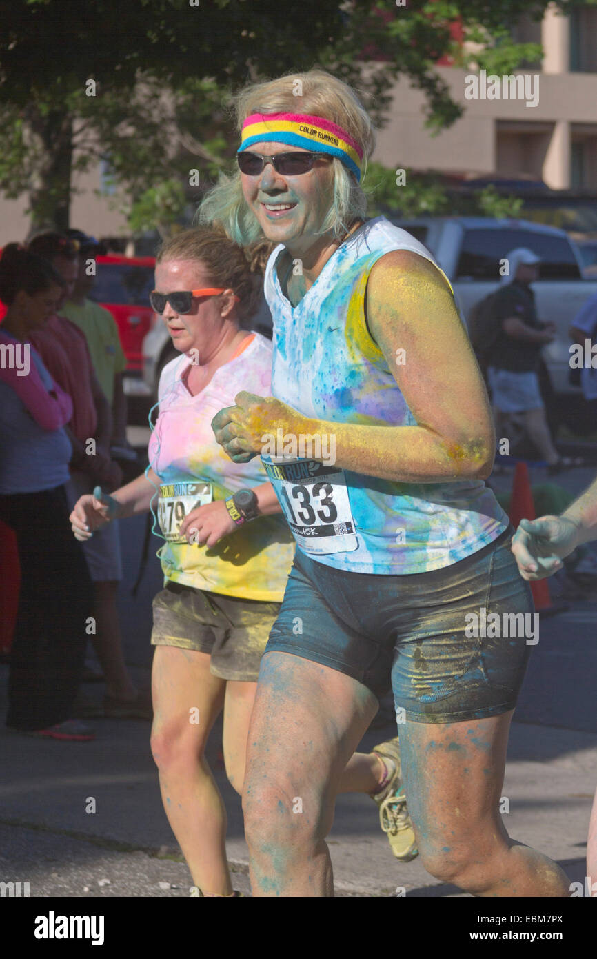 Frauen Läufer spritzte mit bunten Färbungen führen in die glückliche Asheville Color Run Stockfoto