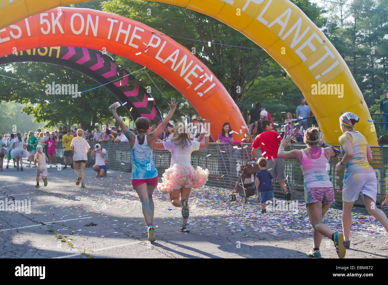 Glücklich Läufer mit bunten Farben bespritzt nähern sich die Ziellinie in Asheville 5K Color Run Stockfoto