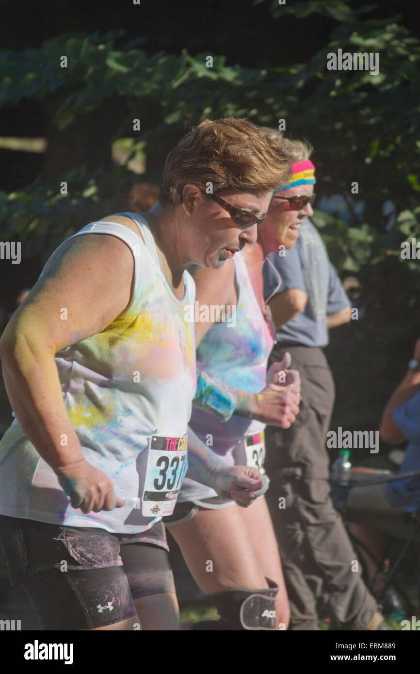 Frauen mit bespritzt färben laufen zusammen die glücklich Asheville 5K Color Run Stockfoto