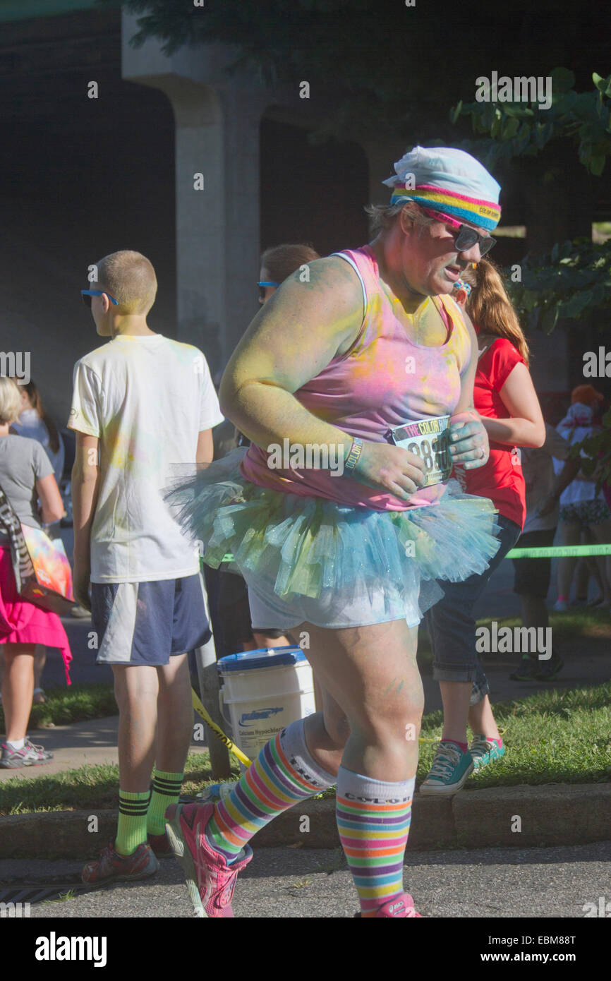 Frau Läufer in Tutus und Kleidung bespritzt mit bunten Farbstoff Rennen in die glückliche Asheville 5K Color Run Stockfoto