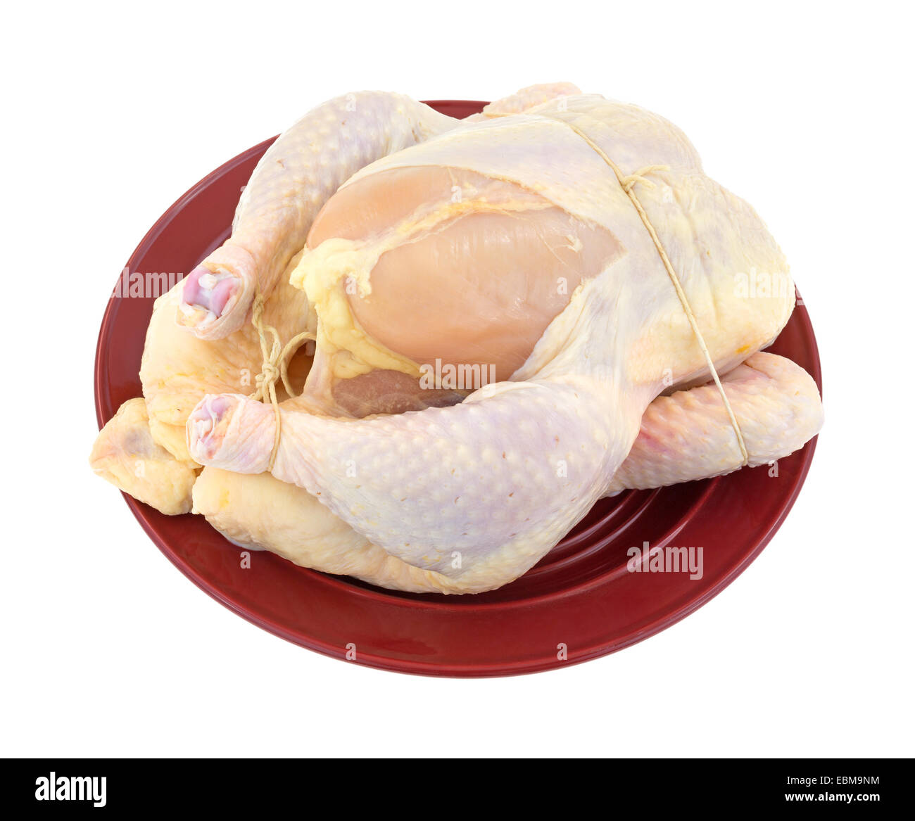 Ganzes Braten Huhn Fachwerk für das Kochen auf einer roten Platte oben auf einem weißen Hintergrund. Stockfoto