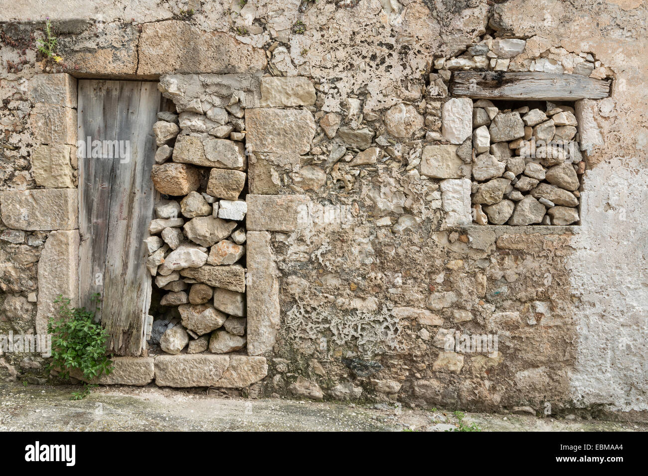 Eine Tür und ein Fenster mit Steinen in einem verlassenen Gebäude in Assos, Kefalonia verstopft. Stockfoto