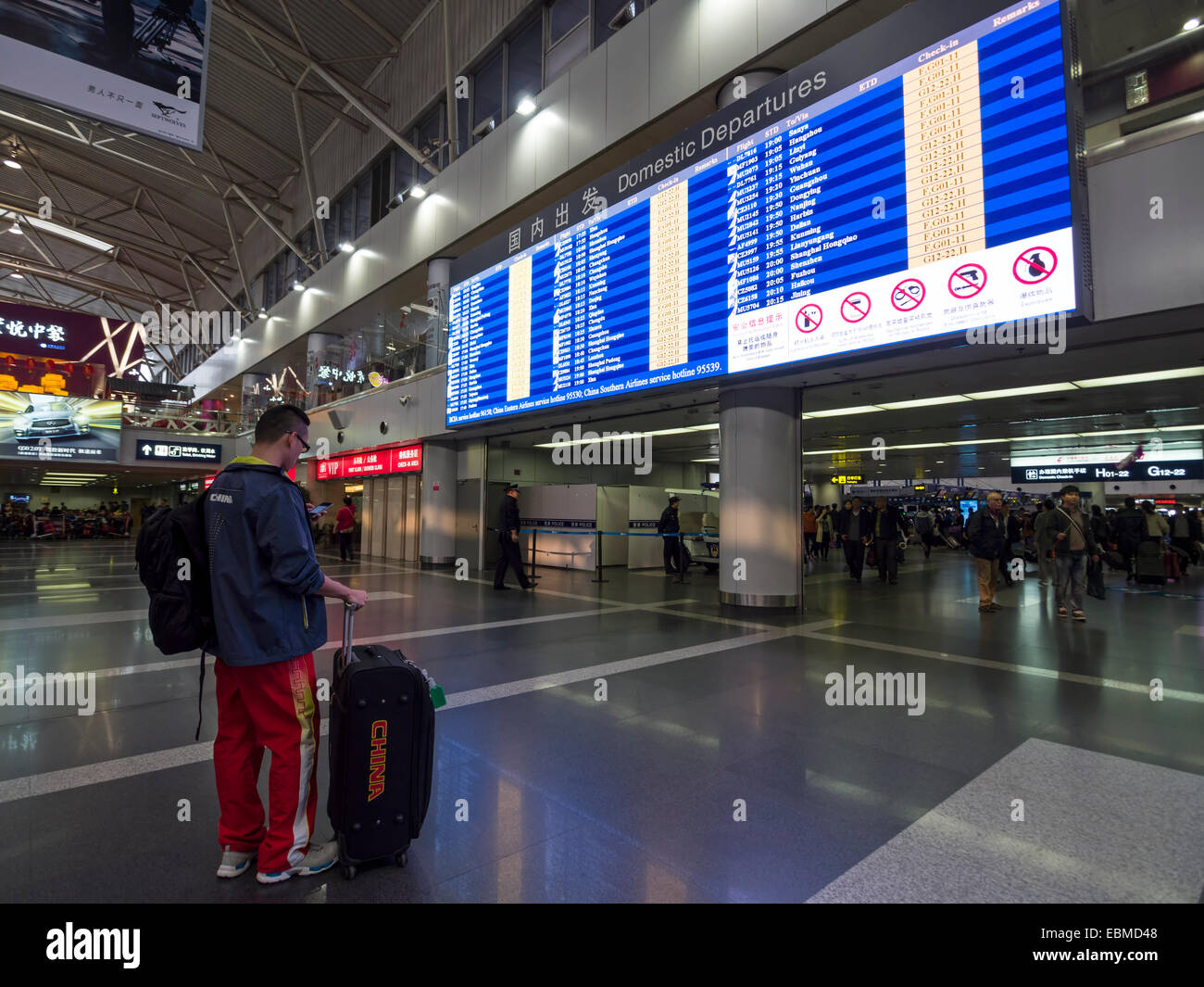 Mann mit Koffer vor Zeitplan Flugtafel an der Beijing Capital International Airport, China Stockfoto