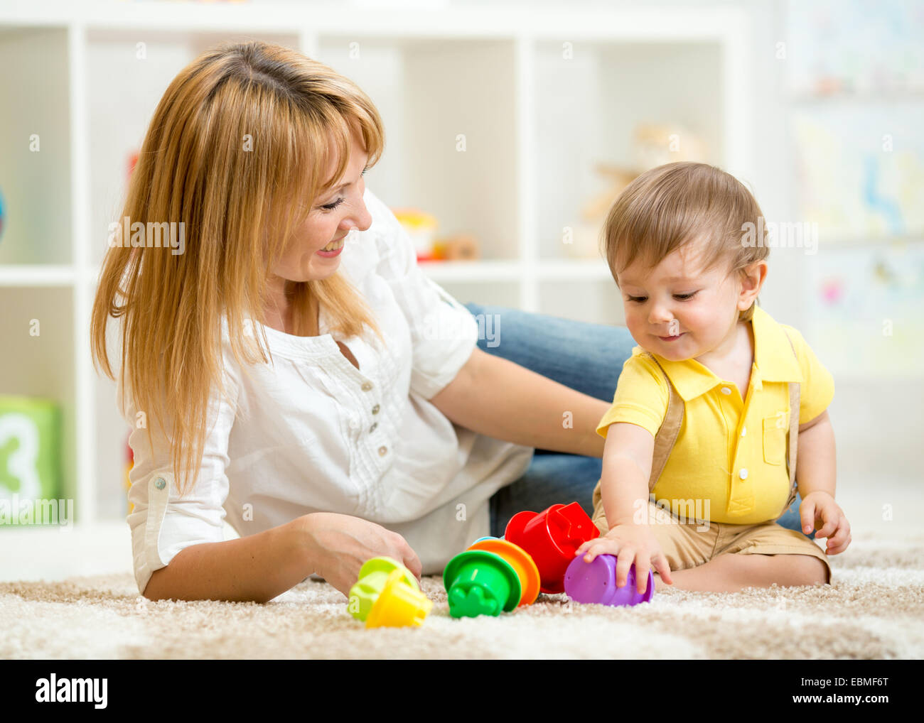 kleines Kind und Frau spielt mit Spielzeug Stockfoto