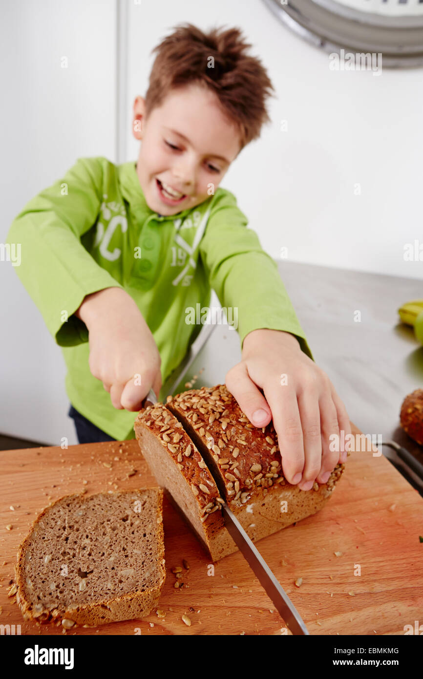 Junge schneiden Scheiben aus Vollkornbrot, Deutschland Stockfoto