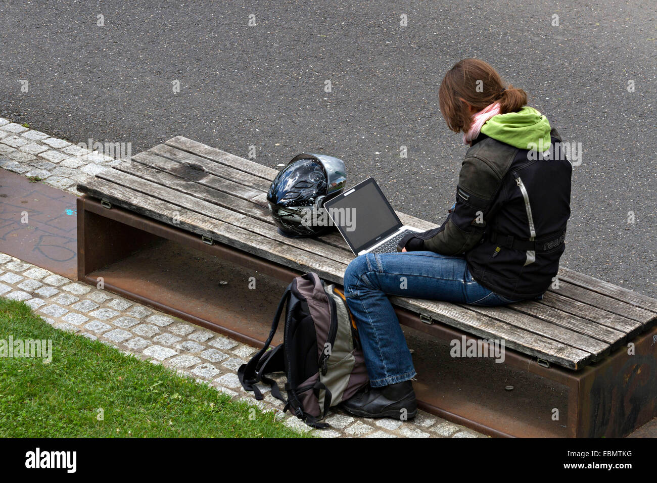 Frau sitzt auf Sitzbank mit einem laptop Stockfoto