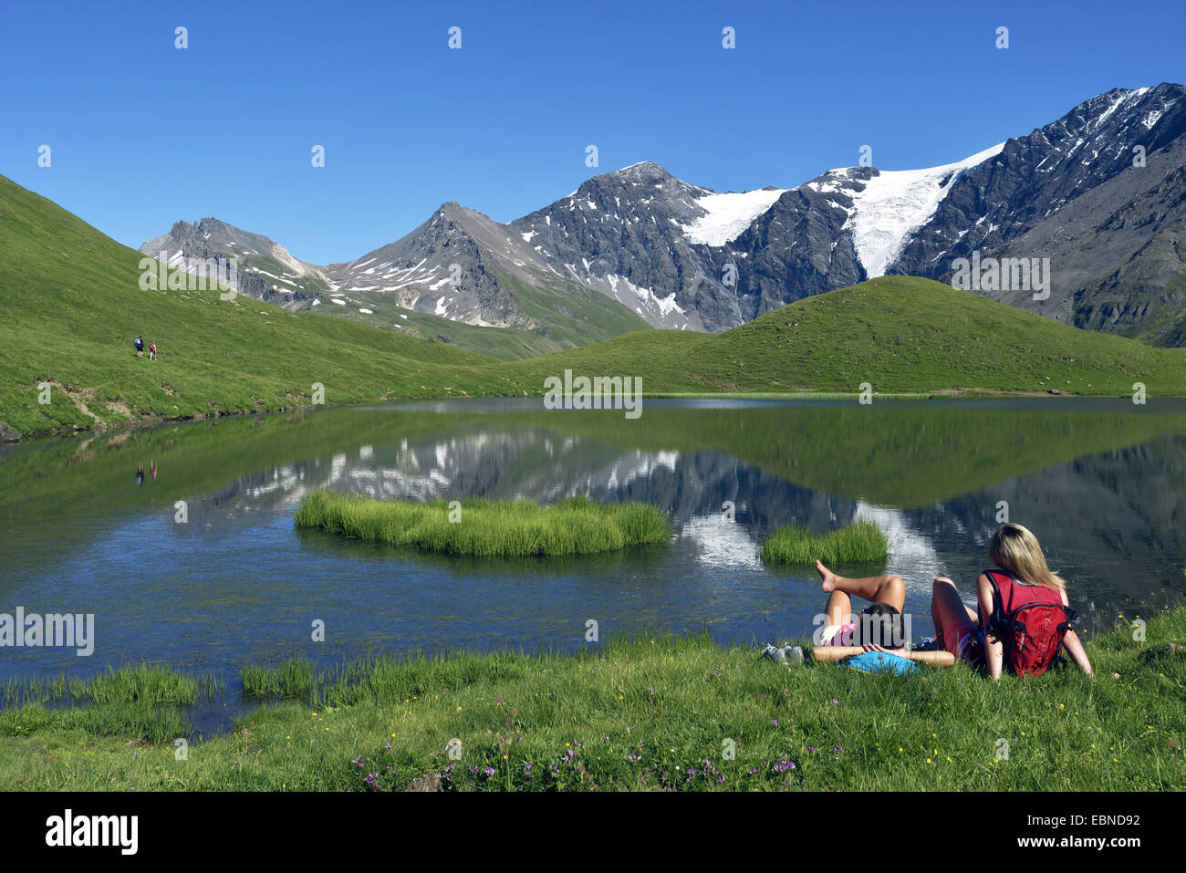 zwei Teenager in Bergwiese sitzen und genießen die Aussicht zum Bergsee, Frankreich, Savoyen, Sainte-Foy-Tarentaise Stockfoto