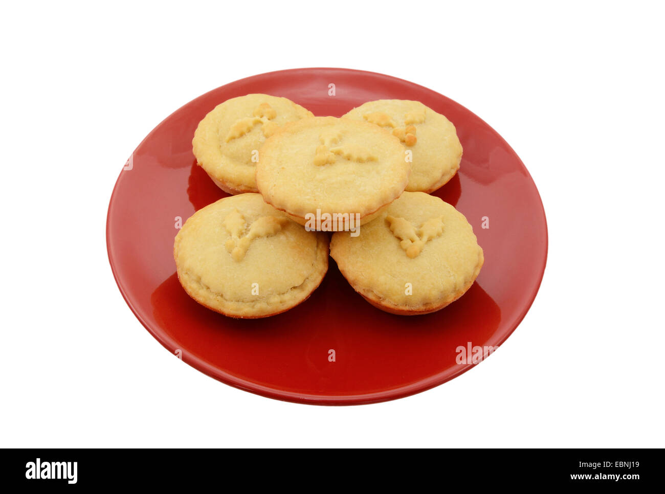 Fünf hausgemachte Mince Pies auf einem festlichen roten Teller, isoliert auf weißem Hintergrund Stockfoto